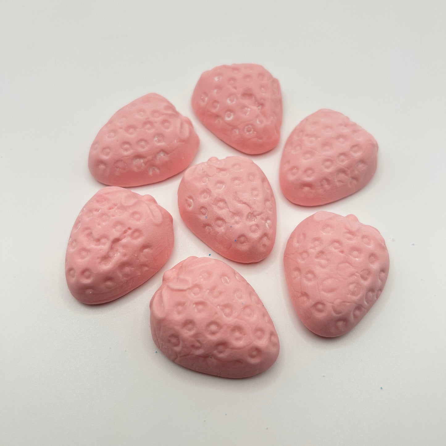 Pink strawberry-shaped candies on a white background